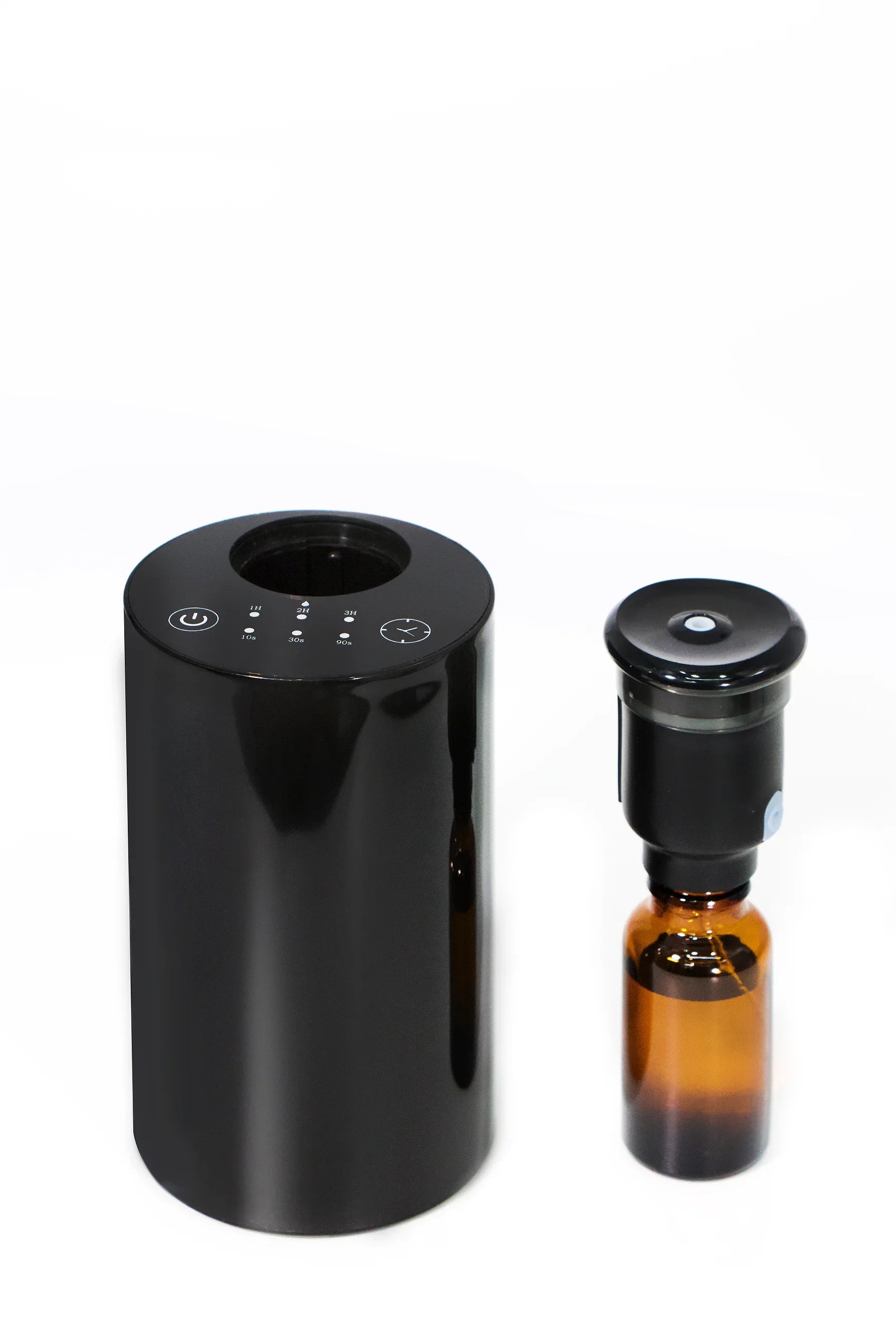 Black essential oil diffuser device with amber glass bottle on white background