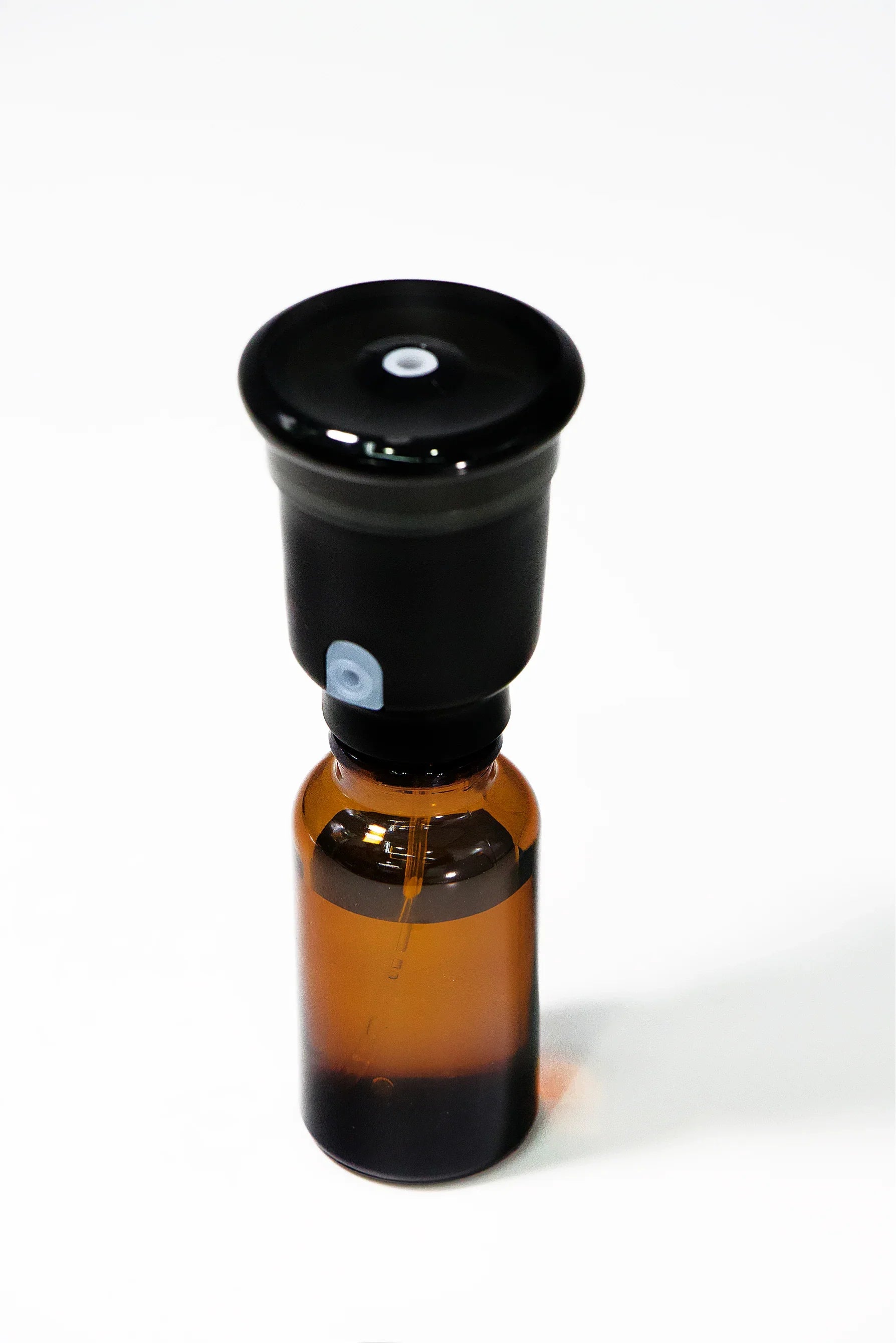 Amber glass bottle with black dropper cap on white background for essential oils or tinctures