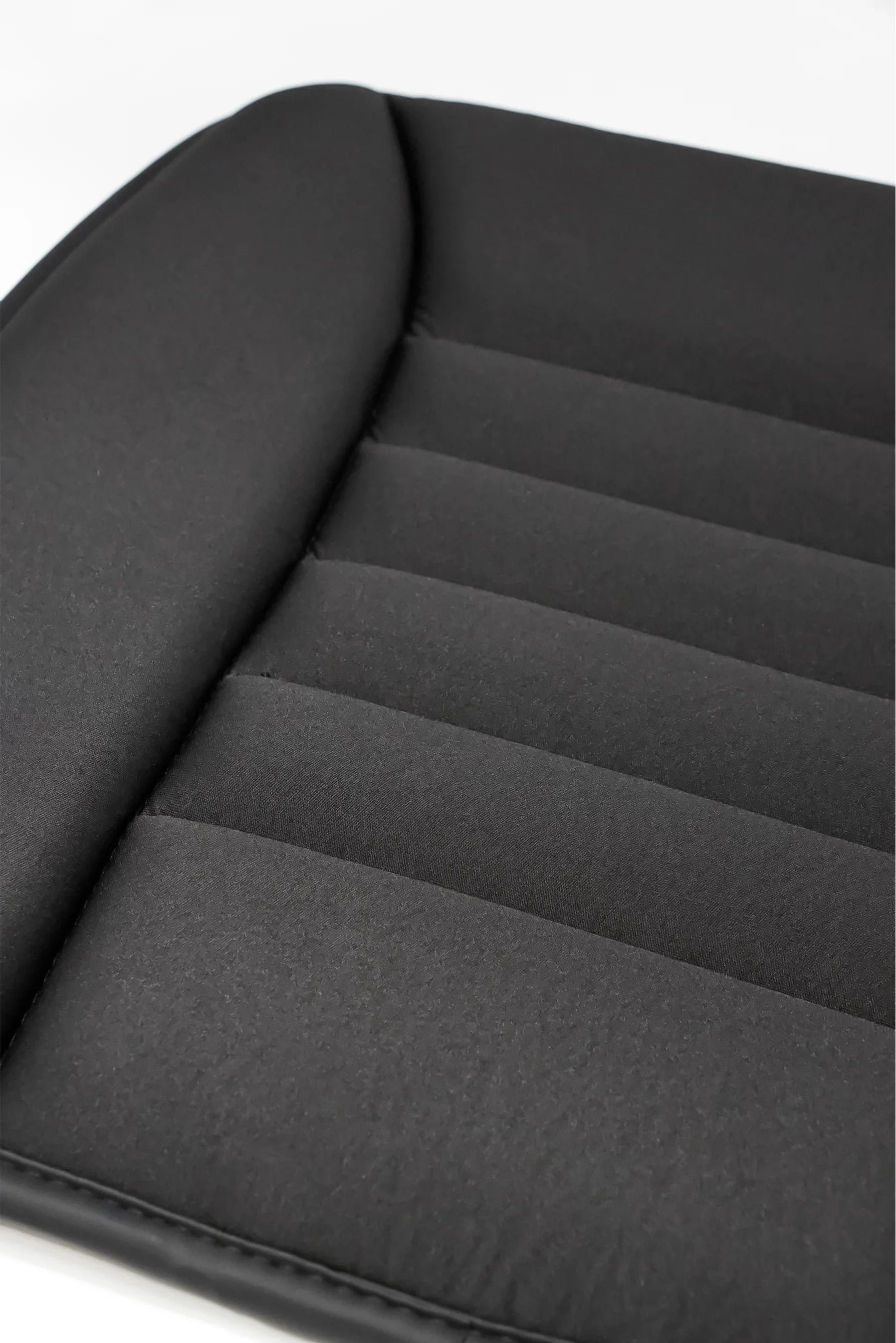 Close-up of black cushioned padded seat with stitched horizontal lines and smooth fabric