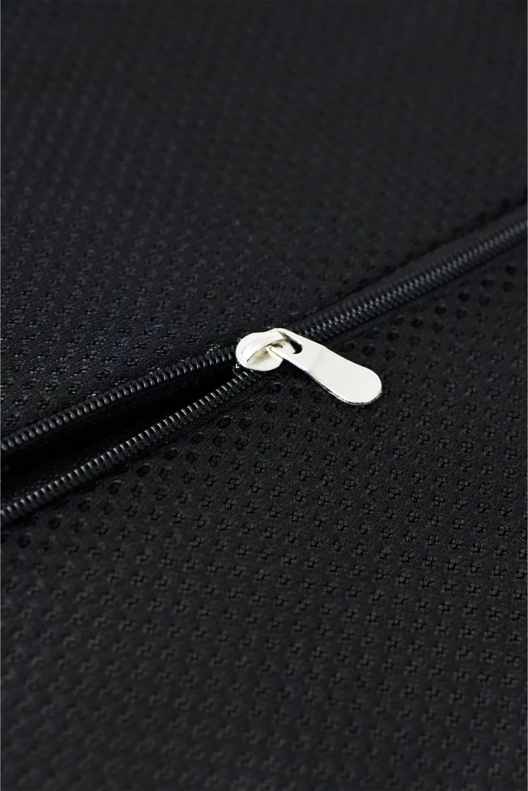 Close-up of a silver zipper on textured black fabric with small perforated holes