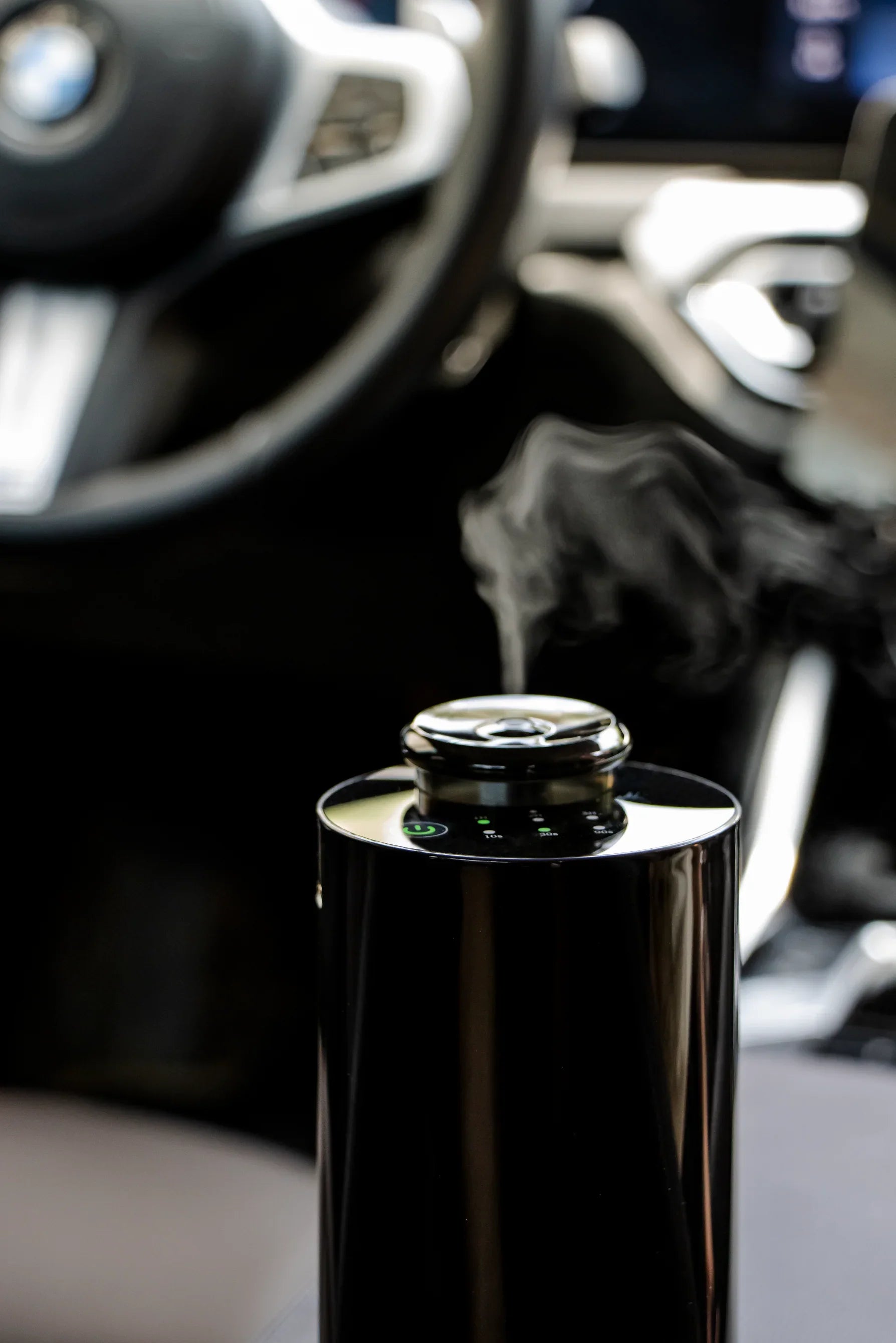 Sleek black car diffuser releasing mist inside a luxury BMW vehicle interior